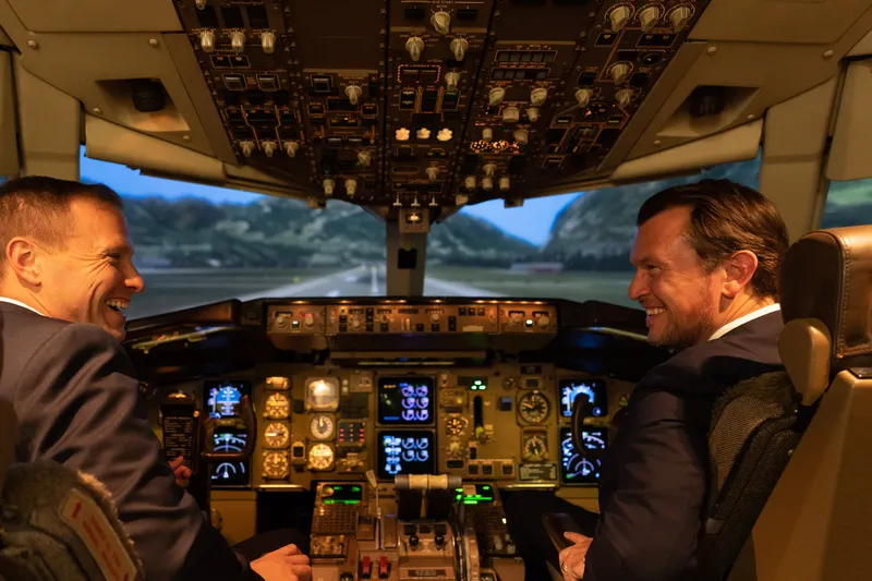 Kunden sitzen im Flugsimulator Cockpit von Lufthansaund haben Spaß